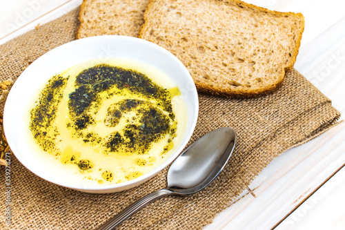 soup with yogurt on light color wooden background. making two slices of wheat next to it.