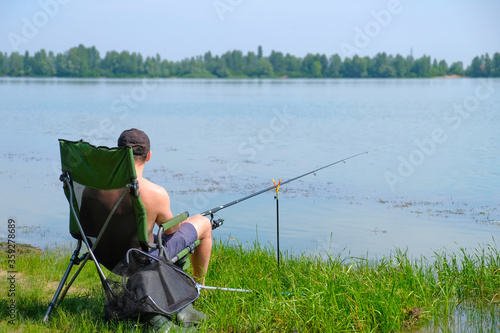 Fisherman on the river in a chair with a fishing rod in his hands. A man on summer fishing on a sunny day.