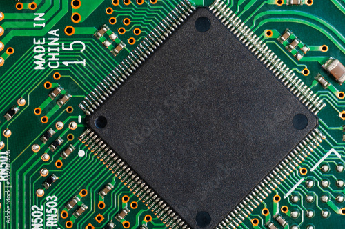 Close-up of electronic circuit board PCB with microchip, processor, integrated circuits, resistances and electronic connections. Top view.