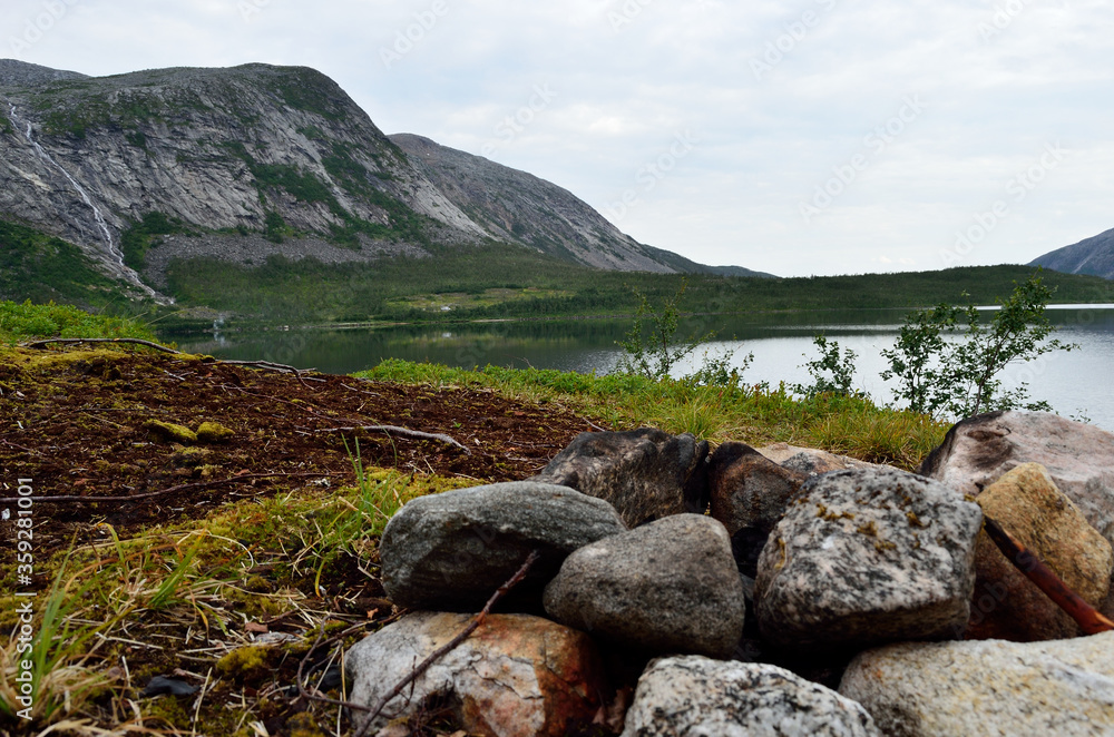 stone camp fire with mountain and lake in background in summer stone camp fire with mountain and lake in background in summer
