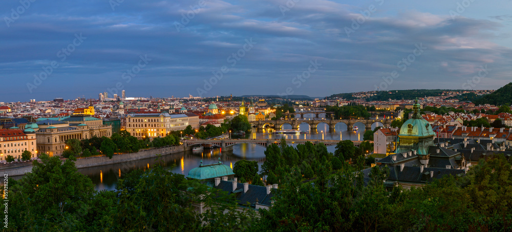  Panoramic view of the  illuminated cityscape and bridges of Prague,  including the famous Charles Bridge and old town. Summer evening , just after sunset time. Czech Republic.