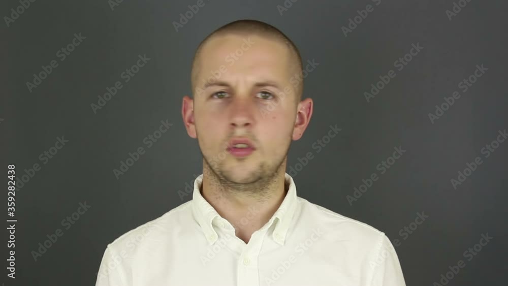 A funny handsome guy says no and shakes his head negatively. Portrait on a gray background. A funny handsome guy says no and shakes his head negatively. Portrait on a gray background.