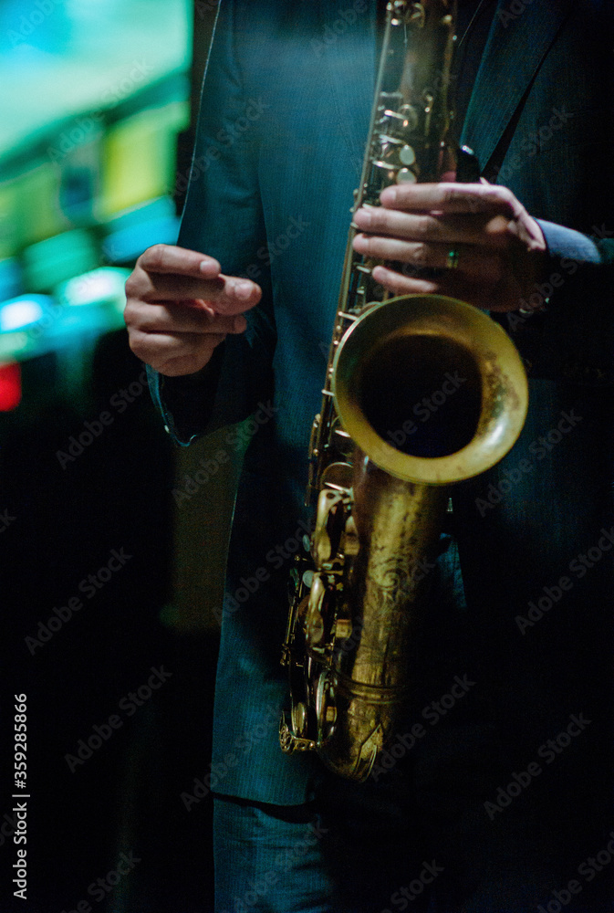 Obraz premium Jazz musician wearing suit snapping finger to count time playing saxophone in a dark neon night club.