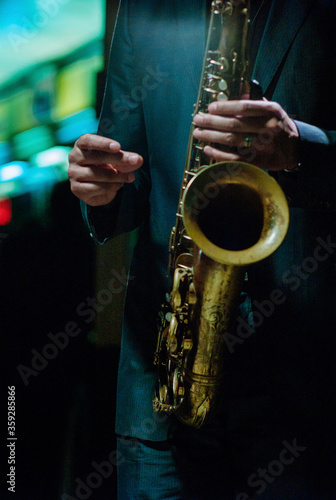 Photography Jazz musician wearing suit snapping finger to count time playing saxophone in a dark neon night club
