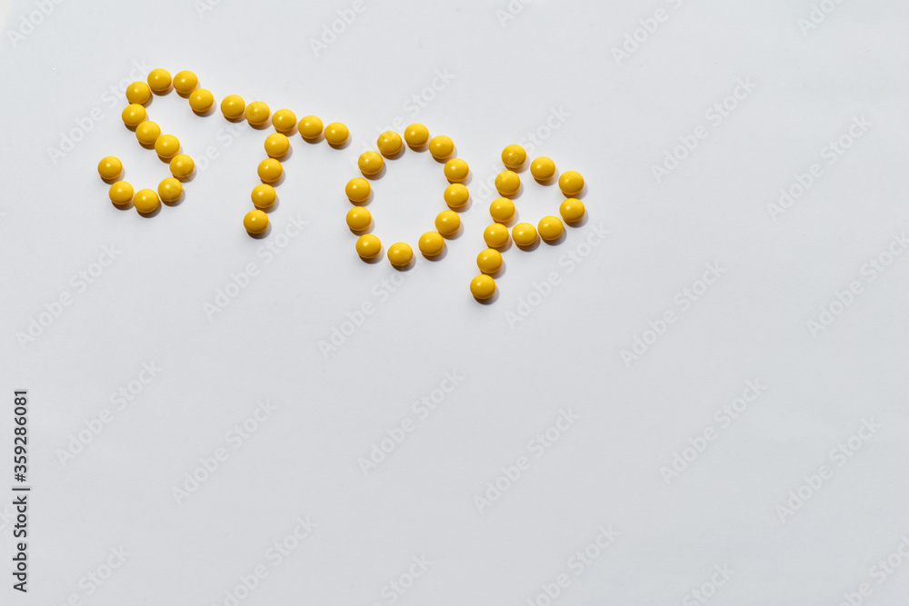 Word STOP made from yellow medical pills on light background. Stop disease. Health care and treatment concept Word STOP made from yellow medical pills on light background. Stop disease. Health care and treatment concept