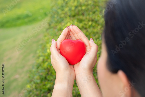 Holding a red heart, health care, love and family concepts, World Heart Day, a woman holding a red heart in her chest,closeup.