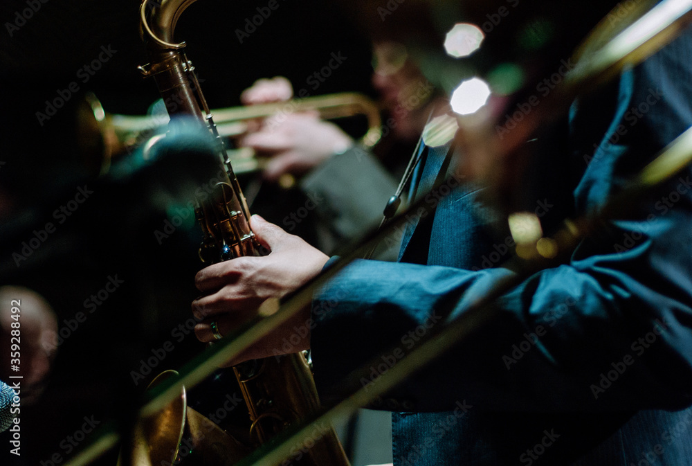 Obraz premium Two Jazz musicians wearing suits playing saxophone and trumpet duet in a dark neon night club.
