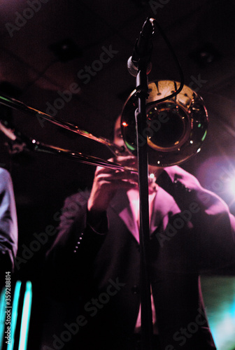 Canvas Print Jazz musician wearing suit playing trombone in a dark neon night club