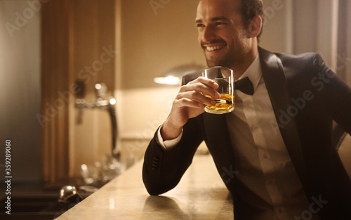 Smiling man having whiskey at night club photo