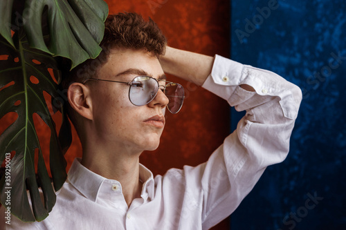 Fashionable young handsome man wearing trendy blue aviator sunglasses. Close up studio portrait with natural light photo