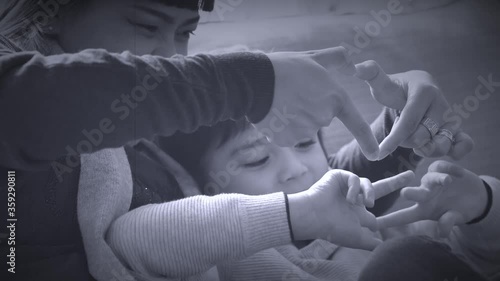 Asian mam and her mixed race son sitting on sofa making love signs, Mother and son relaxing and having fun at home in black and white retro filter, Multi ethnic of family concept