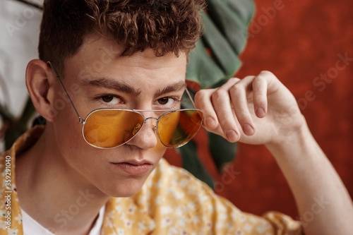 Foto Fashionable young handsome man wearing trendy yellow aviator sunglasses