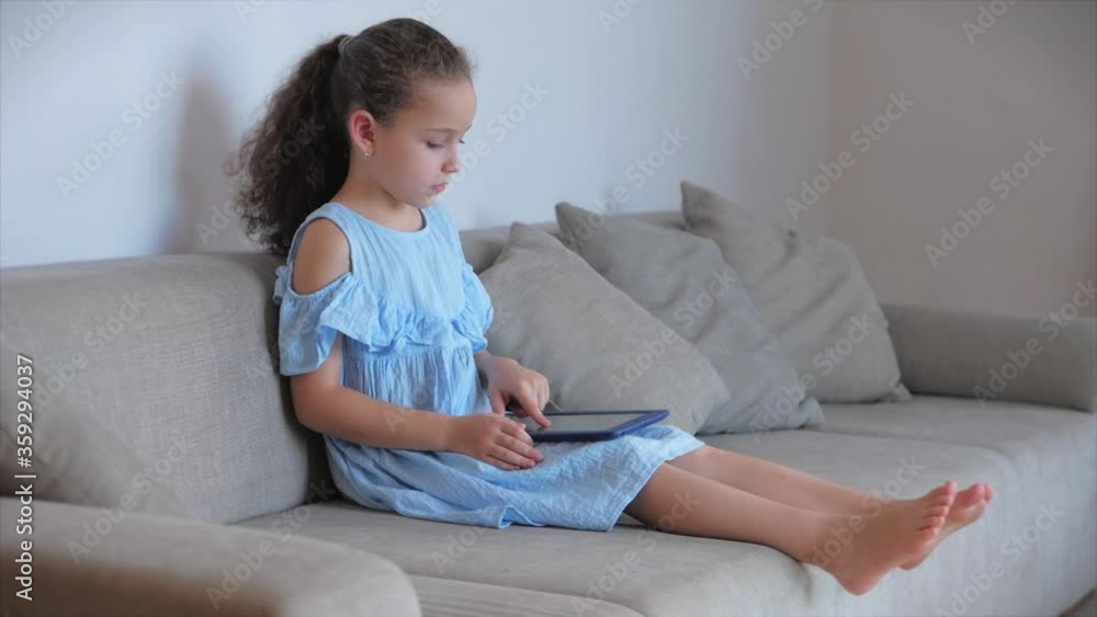 Happy Little Girl or child playing at home relaxing use a smartphone cuddling sit on sofa daughter and son,look at the screen of a cell phone, watch cartoons.
