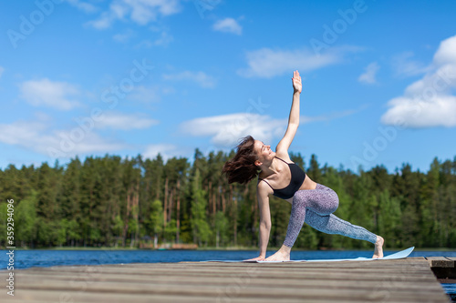 Woman exercising yoga and do exercise. fitness lifestyle at the outdoors nature background. Sunny day on lake