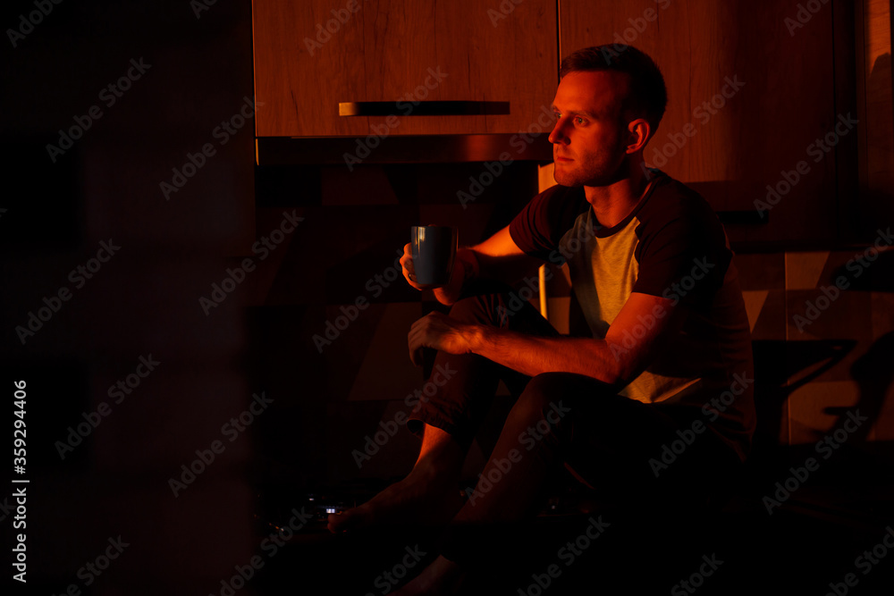 A man sits in the kitchen in the sunset light and drinks coffee A man sits in the kitchen in the sunset light and drinks coffee