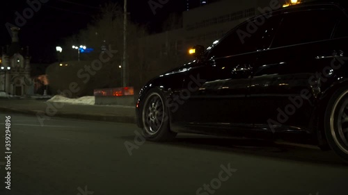 Black car on highway, road, slow driving. Footage. View of car lights in night city.