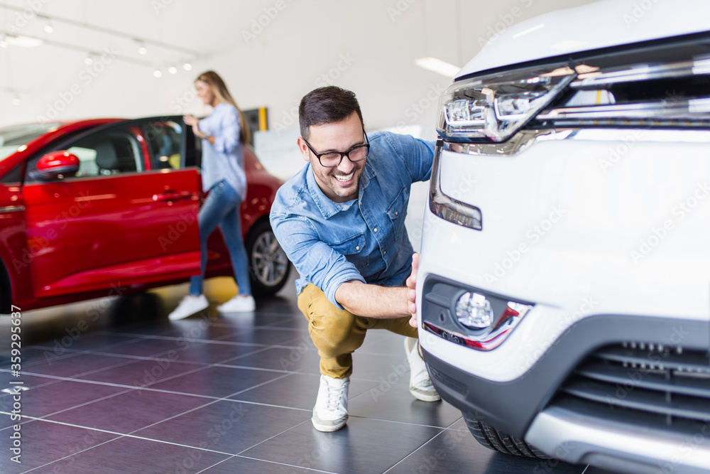 Young handsome man choosing a new car at car showroom.. Young handsome man choosing a new car at car showroom..