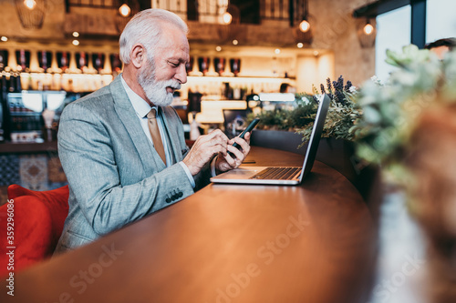 Mature beard businessmen working on laptop in modern cafe.