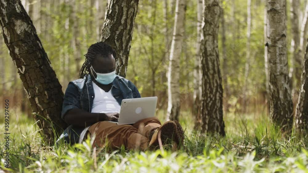 New normal. Remote work concept. African man using laptop in the nature. New normal. Remote work concept. African man using laptop in the nature.