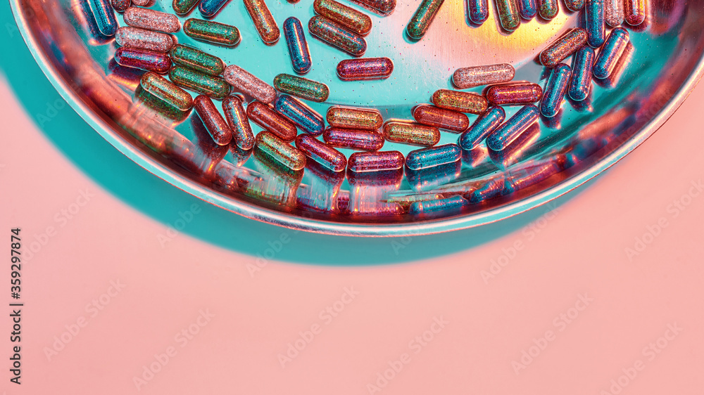 Obraz premium Creative concept with many colorful glitter pills scattered, lying randomly in round metal box. Minimal style, art concept