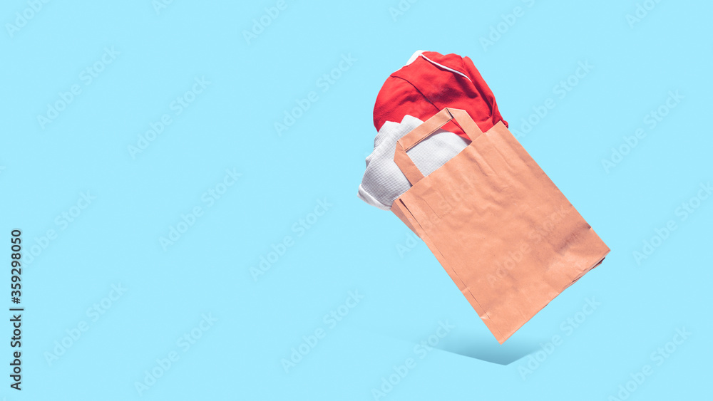 Flying shopping paper bag with purchases. Concept of consumerism, ease of shopping. Copy space trend pastel colors. Flying shopping paper bag with purchases. Concept of consumerism, ease of shopping. Copy space trend pastel colors.