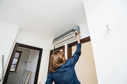 Engineer woman testing trying to repair newly installed air conditioner wall ac unit