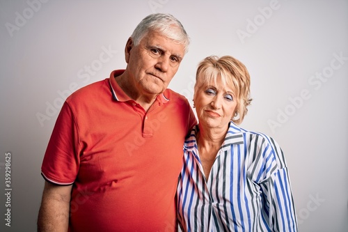 Senior beautiful couple standing together over isolated white background looking sleepy and tired, exhausted for fatigue and hangover, lazy eyes in the morning.