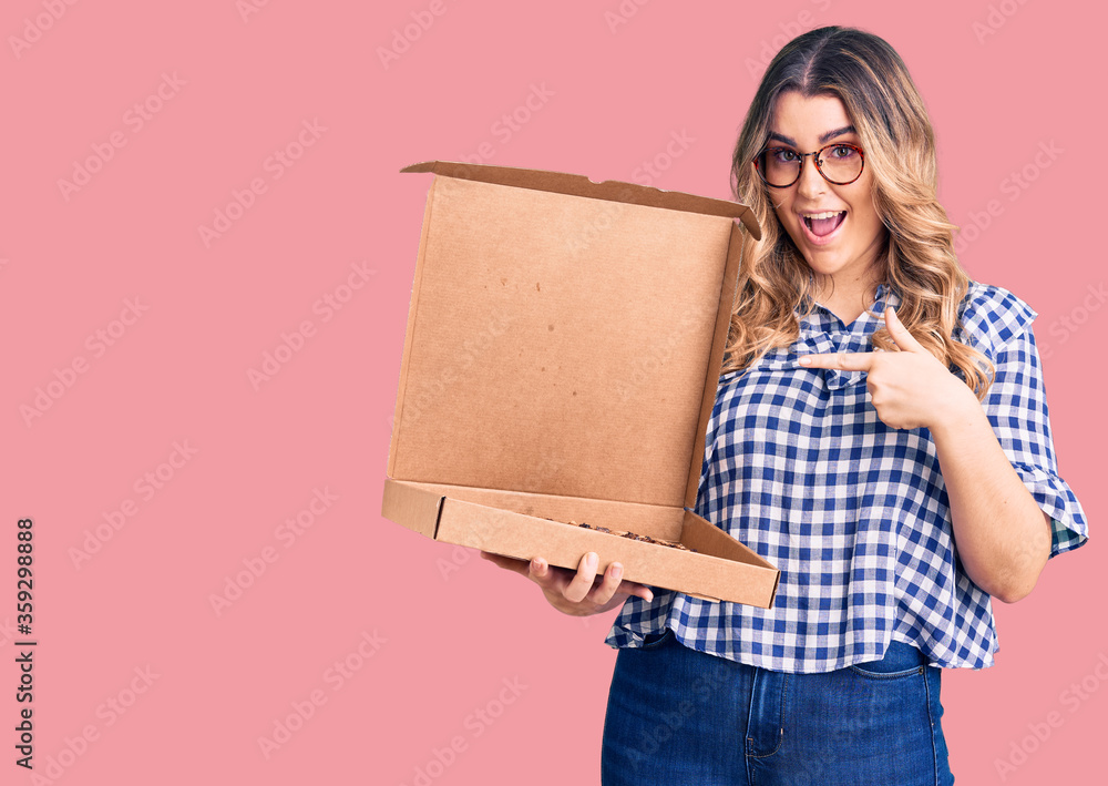 Young caucasian woman holding delivery pizza box pointing finger to one self smiling happy and proud Young caucasian woman holding delivery pizza box pointing finger to one self smiling happy and proud