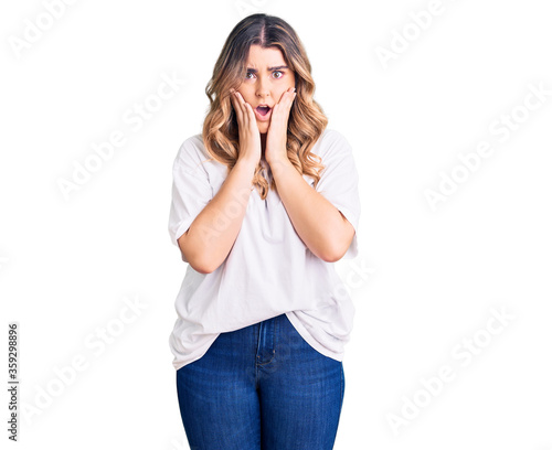 Young caucasian woman wearing casual clothes afraid and shocked, surprise and amazed expression with hands on face