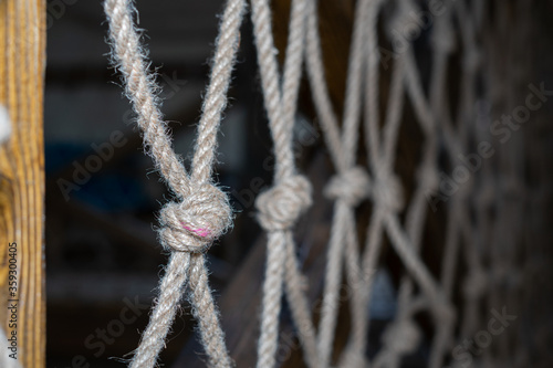 Wall made of rope mesh. Soft focus. Knot made of gray rope