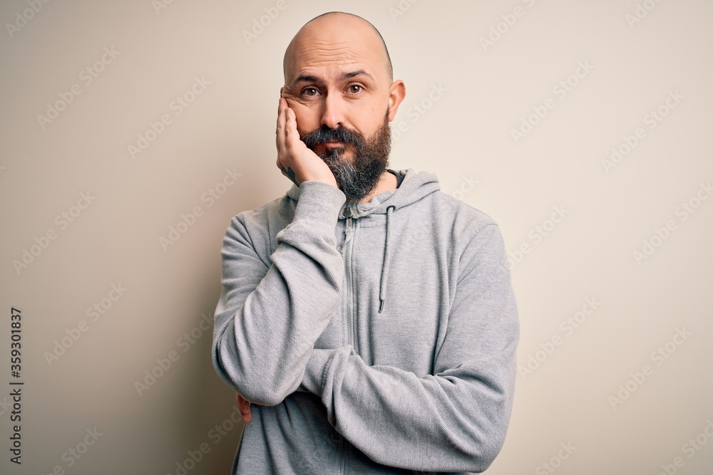 Handsome sporty bald man with beard wearing sweatshirt standing over pink background thinking looking tired and bored with depression problems with crossed arms. Handsome sporty bald man with beard wearing sweatshirt standing over pink background thinking looking tired and bored with depression problems with crossed arms.