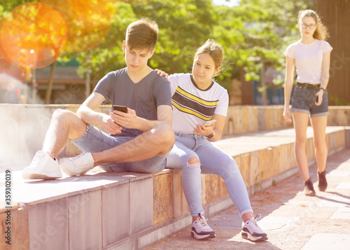 Three teenagers with smartphones are talking about play on walk