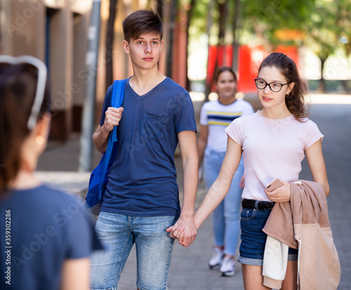 Happy teenage couple strolling along city street in summer