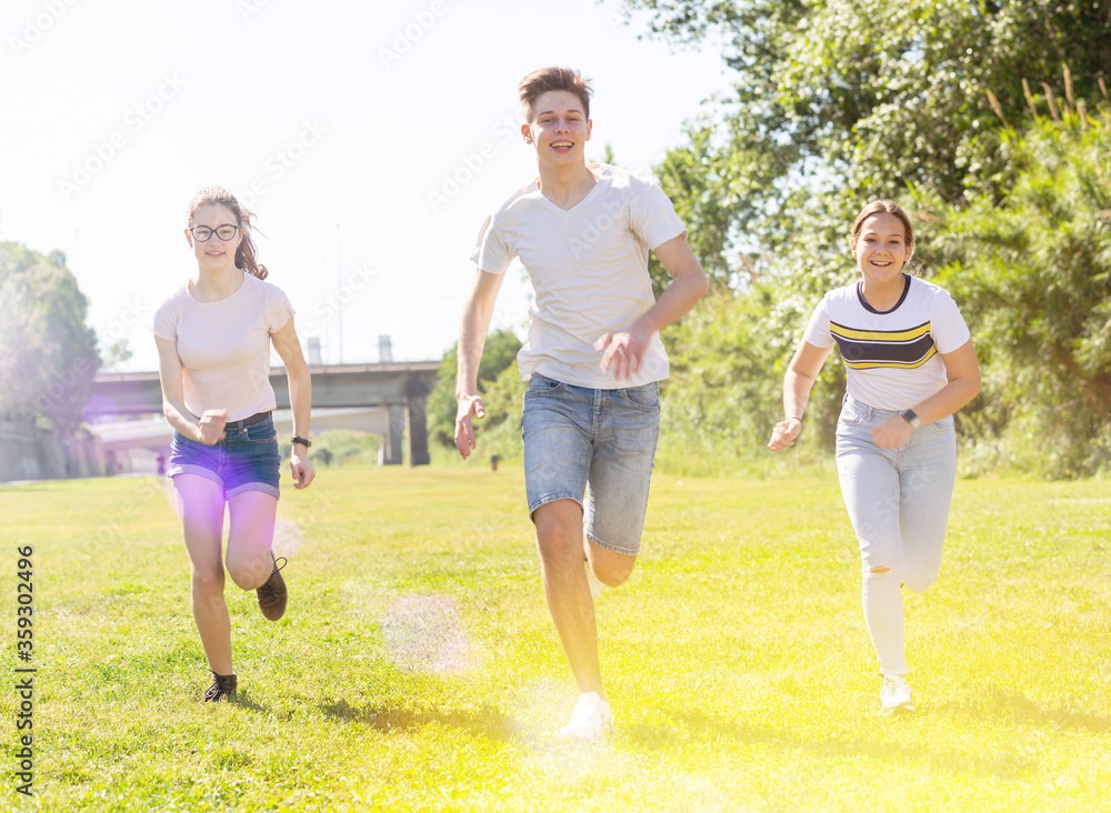 Cheerful teenagers are jogging together in the park