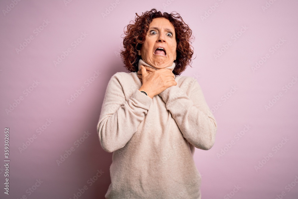 Middle age beautiful curly hair woman wearing casual turtleneck sweater over pink background shouting suffocate because painful strangle. Health problem. Asphyxiate and suicide concept. Middle age beautiful curly hair woman wearing casual turtleneck sweater over pink background shouting suffocate because painful strangle. Health problem. Asphyxiate and suicide concept.