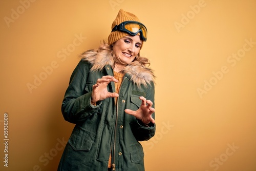 Middle age beautiful blonde skier woman wearing snow sportwear and ski goggles disgusted expression, displeased and fearful doing disgust face because aversion reaction.