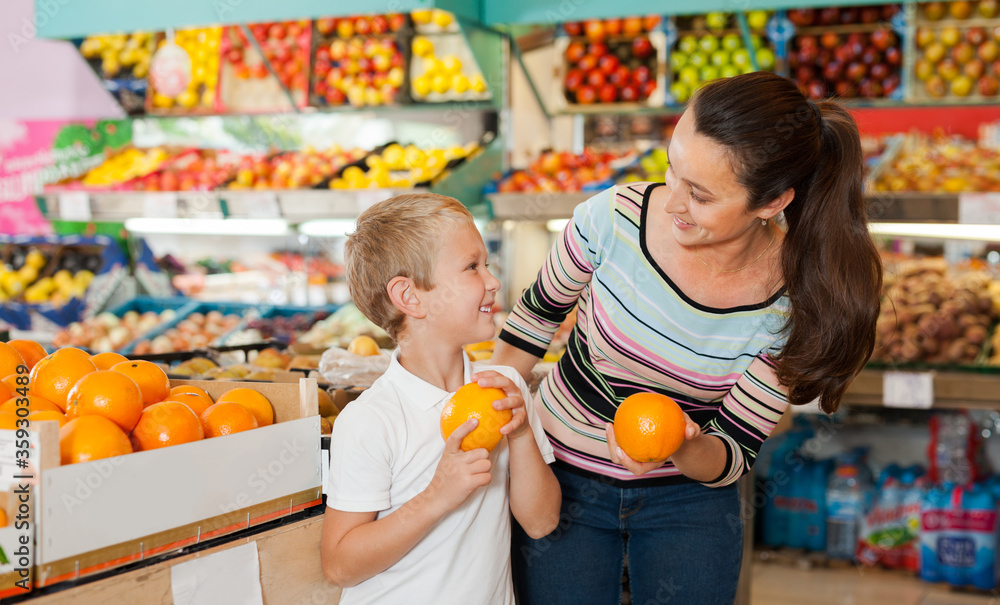 Fototapeta premium boy with woman choosing fresh oranges