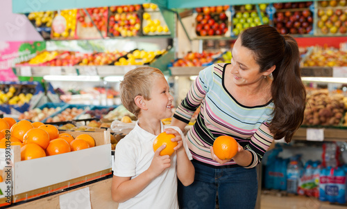  boy with woman choosing fresh oranges