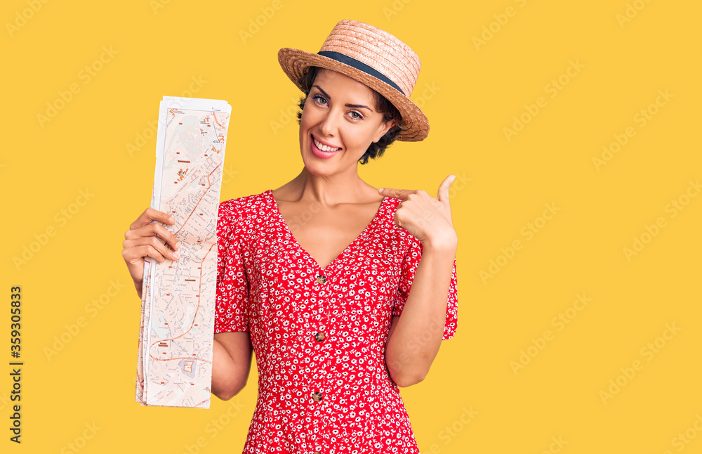 Young beautiful woman wearing summer hat holding map pointing finger to one self smiling happy and proud Young beautiful woman wearing summer hat holding map pointing finger to one self smiling happy and proud