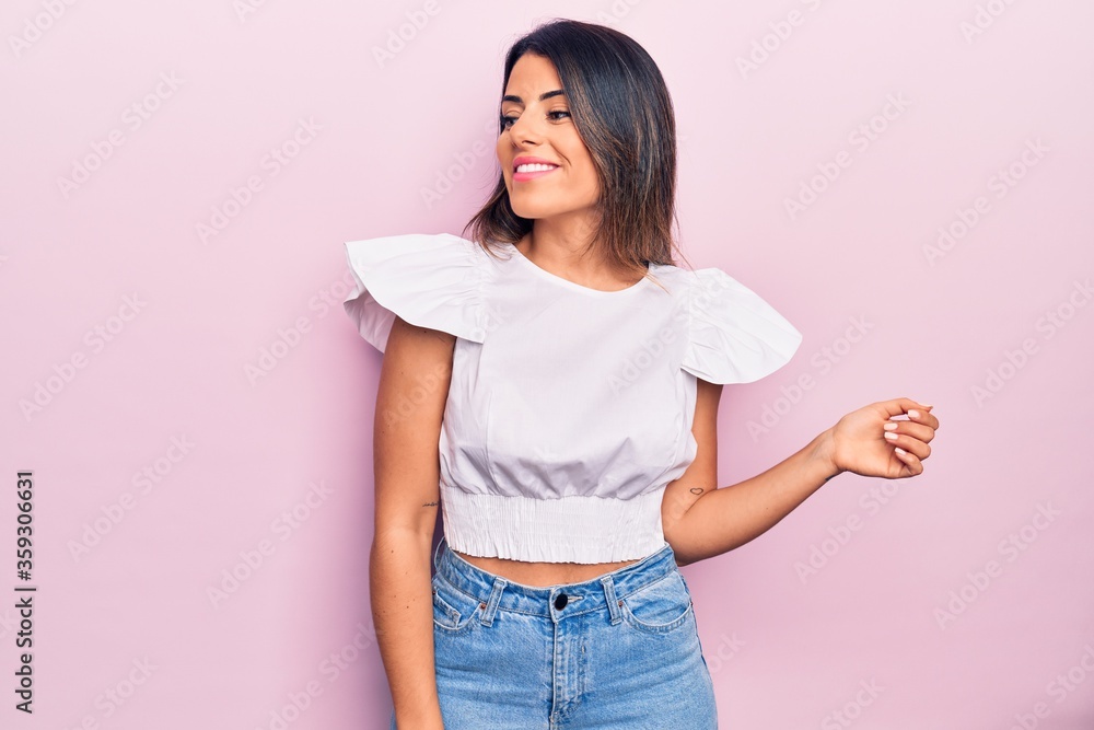 Young beautiful brunette woman wearing casual clothes smiling happy and confident. Standing with smile on face over isolated pink background Young beautiful brunette woman wearing casual clothes smiling happy and confident. Standing with smile on face over isolated pink background