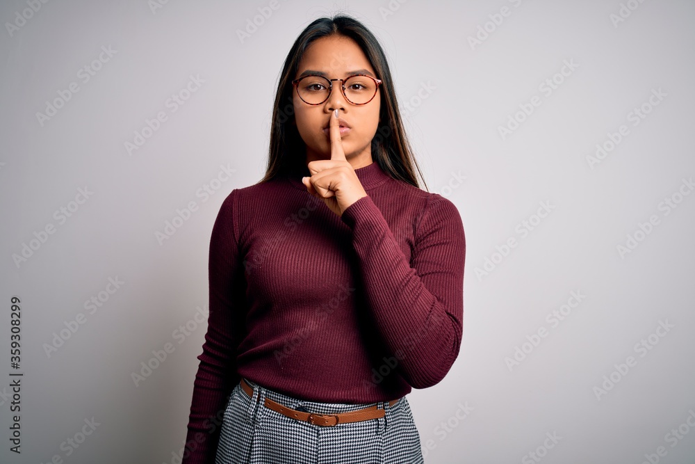 Beautiful asian business woman wearing casual sweater and glasses over white background asking to be quiet with finger on lips. Silence and secret concept. Beautiful asian business woman wearing casual sweater and glasses over white background asking to be quiet with finger on lips. Silence and secret concept.