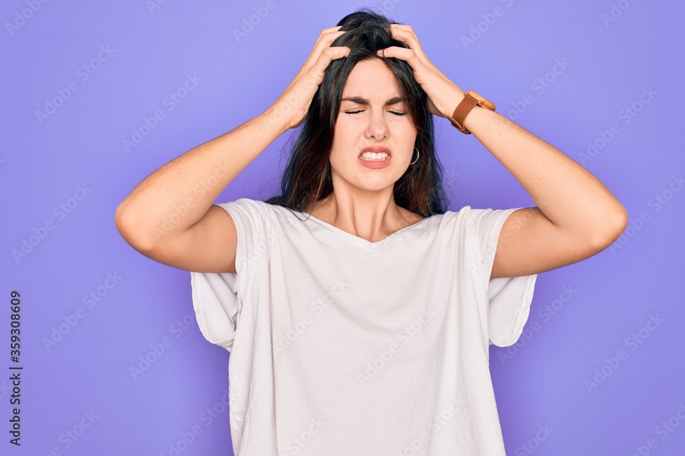 Young beautiful brunette woman wearing casual white t-shirt over purple background suffering from headache desperate and stressed because pain and migraine. Hands on head. Young beautiful brunette woman wearing casual white t-shirt over purple background suffering from headache desperate and stressed because pain and migraine. Hands on head.