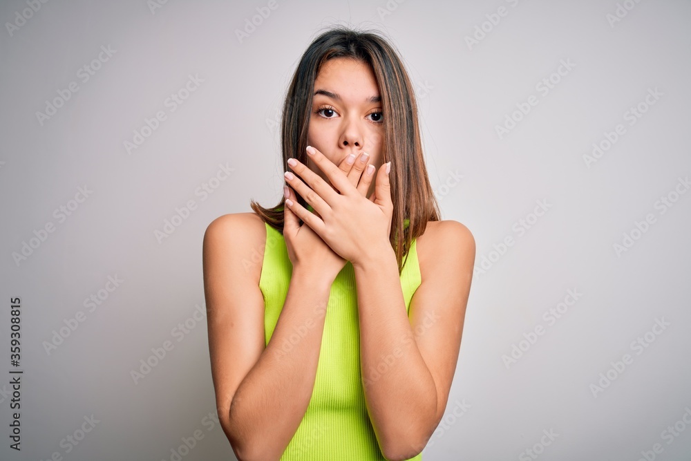 Young beautiful brunette girl wearing casual summer t-shirt over isolated white background shocked covering mouth with hands for mistake. Secret concept. Young beautiful brunette girl wearing casual summer t-shirt over isolated white background shocked covering mouth with hands for mistake. Secret concept.