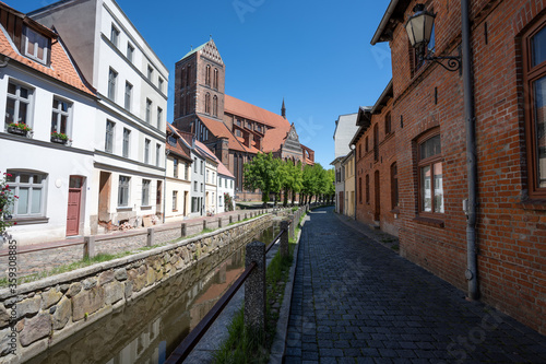 Fototapeta Naklejka Na Ścianę i Meble -  Church St. Nicholas (Nikolaikirche) and canal in the old town of Wismar against a blue sky, the hanseatic city is a famous tourist destination at the Baltic Sea in northern Germany