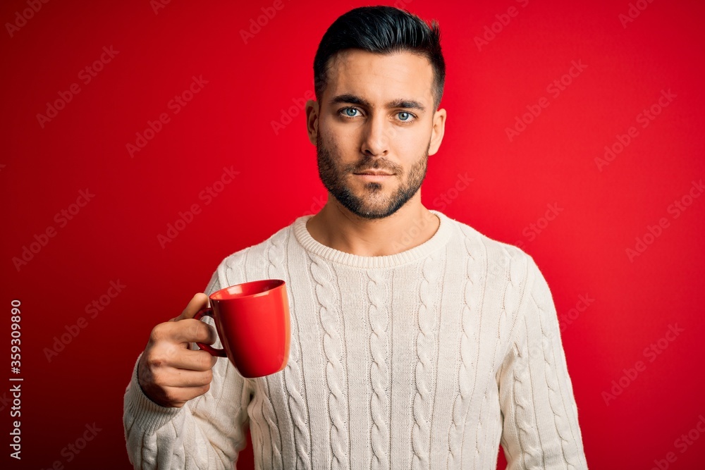 Young handsome man drinking a cup of hot coffee over red isolated background with a confident expression on smart face thinking serious Young handsome man drinking a cup of hot coffee over red isolated background with a confident expression on smart face thinking serious