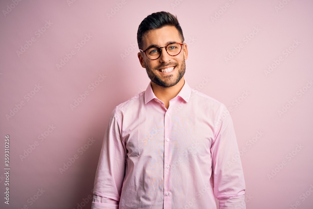 Young handsome man wearing elegant shirt and glasses standing over pink background with a happy and cool smile on face. Lucky person. Young handsome man wearing elegant shirt and glasses standing over pink background with a happy and cool smile on face. Lucky person.