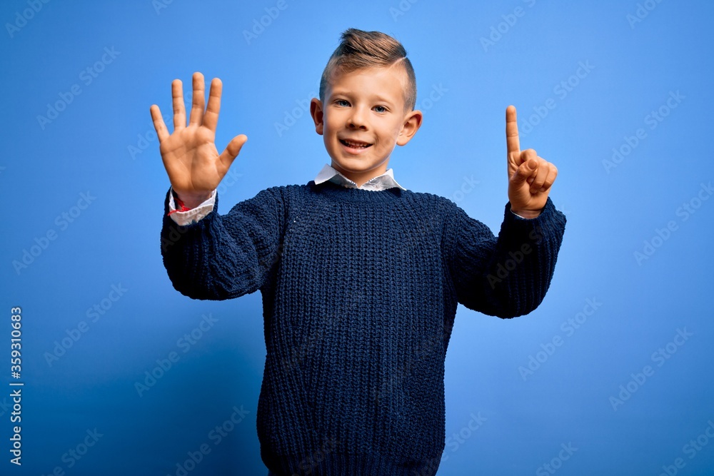 Young little caucasian kid with blue eyes wearing winter sweater over blue background showing and pointing up with fingers number six while smiling confident and happy. Young little caucasian kid with blue eyes wearing winter sweater over blue background showing and pointing up with fingers number six while smiling confident and happy.