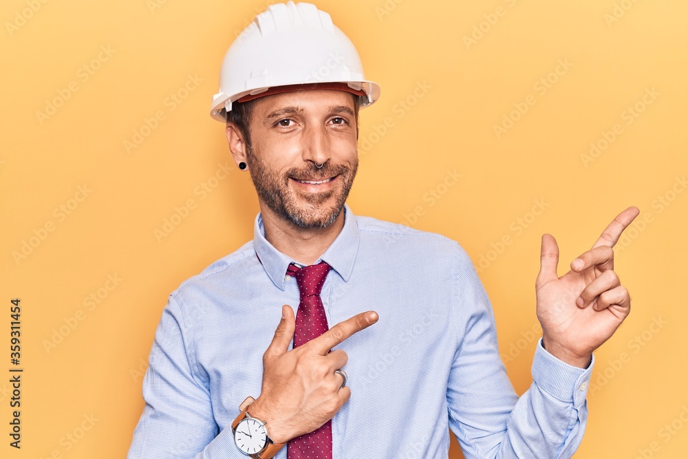 Young handsome man wearing architect hardhat smiling and looking at the camera pointing with two hands and fingers to the side. Young handsome man wearing architect hardhat smiling and looking at the camera pointing with two hands and fingers to the side.
