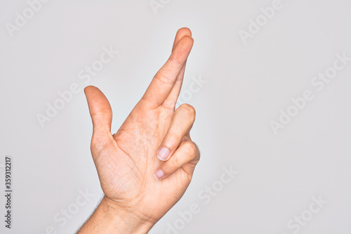 Hand of caucasian young man showing fingers over isolated white background gesturing fingers crossed, superstition and lucky gesture, lucky and hope expression