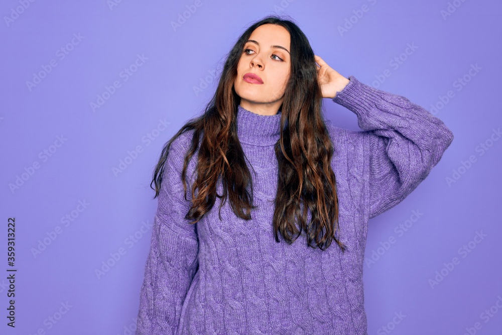 Fototapeta premium Young beautiful woman wearing casual turtleneck sweater standing over purple background confuse and wondering about question. Uncertain with doubt, thinking with hand on head. Pensive concept.